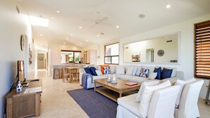 A spacious living area with a sofa, coffee table, and a dining area with chairs. - Hale Lani 2 - Oceanview Penthouse Paradise (Sunshine Beach)