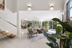 Relax in a spacious living area with a high ceiling, sofa, and armchairs, offering a view of the outdoors.
