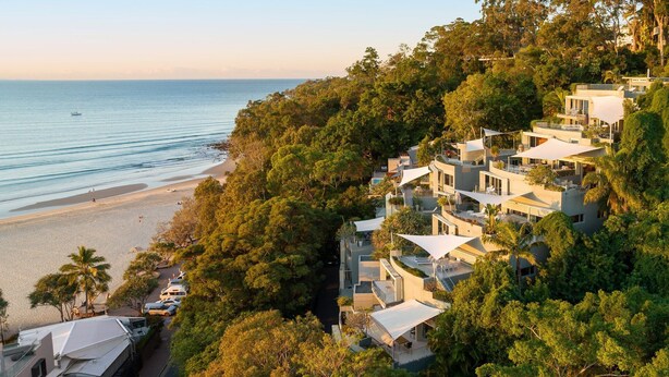 Un quartier résidentiel en bord de mer, avec des maisons modernes, une plage et une vue dégagée sur la mer.