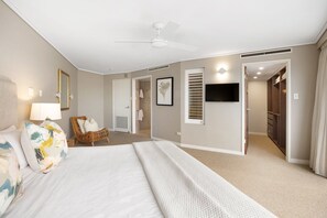 A hotel room with a bed, a chair, a ceiling fan, a TV, and a walk-in closet.