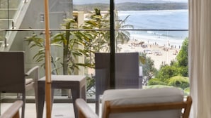 Un balcon donnant sur une plage, avec une chaise et une table.