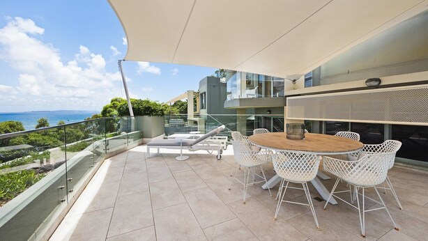 Eine moderne Terrassenanlage im Freien mit einem runden Tisch und weißen Stühlen, mit Blick auf eine reizvolle Landschaft.