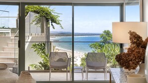 Ein Balkon mit Blick auf Strand und Meer, ausgestattet mit Stühlen und einem Tisch.