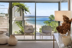 Een balkon met uitzicht op het strand en de oceaan, voorzien van stoelen en een tafel.