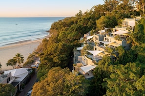 A coastal residential area with modern houses, a beach, and a clear view of the sea.