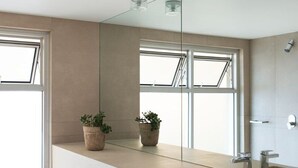 Un baño moderno con un espejo grande, un lavamanos y dos plantas en macetas sobre la encimera.