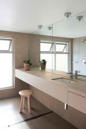 A modern bathroom with a large mirror, a sink, and two potted plants on the countertop.