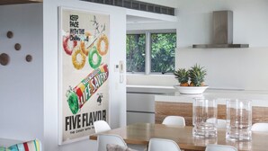 Una cocina moderna con comedor, que incluye un cartel de una barra de chocolate, una planta en maceta y vistas al exterior con vegetación.