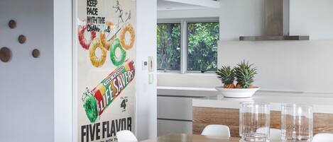 Una cocina moderna con comedor, que incluye un cartel de una barra de chocolate, una planta en maceta y vistas al exterior con vegetación.