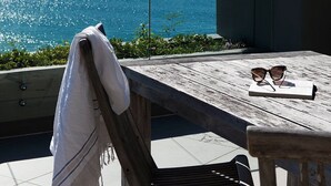 Una terraza de madera con una mesa y sillas, con vista a un cuerpo de agua.
