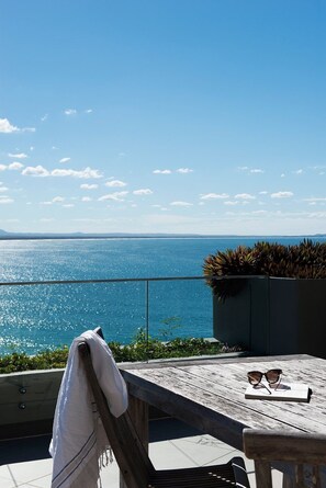 A wooden deck with a table and chairs, overlooking a body of water.