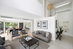 A modern living room with a grey sofa, a coffee table, and a dining area with a table and chairs.