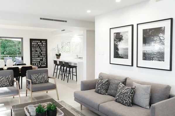 A modern living room with a grey sofa, black and white patterned cushions, and a coffee table with decorative items.