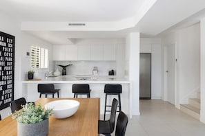 A modern kitchen with white cabinets, a central island, and black chairs.
