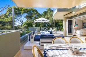 Relax in a serene outdoor space with a comfortable seating area, dining table, and lush surroundings.