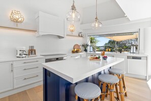 A modern kitchen with a large island, bar stools, and a view of the outdoors.