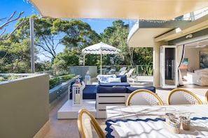 A sunlit outdoor patio with a dining table, chairs, and lounge chairs.