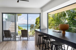 A modern kitchen with a large window overlooking a tropical landscape.