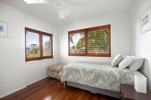 A bedroom with a bed, a nightstand, a window with blinds, and a ceiling fan. - The Islander - Tropical Noosa Getaway (Noosa)