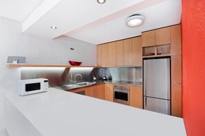 A modern kitchen with a white countertop, stainless steel appliances, and wooden cabinets.