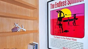 Een boekenplank met boeken en een ingelijst filmplakat aan de muur.