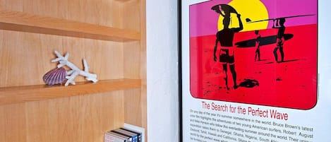 Estante com livros e um pôster de filme emoldurado na parede.