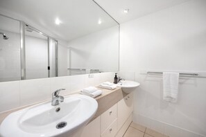 Ein modernes Badezimmer mit großem Spiegel, Waschbecken und Duschbereich.