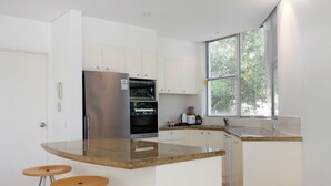 Una cocina moderna con horno empotrado, refrigerador y ventana con persianas.