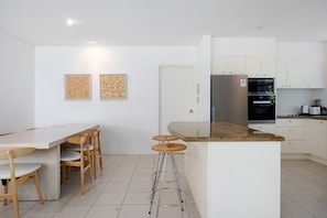 Una cocina moderna con barra, armarios blancos y piso de baldosas.