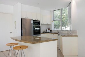 Enjoy cooking in this well-equipped kitchen with a central island, white cabinetry, and an oven.