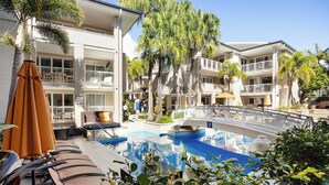 A hotel pool area with lounge chairs, a small pool, and surrounding greenery. - Laguna 117 - Poolside, Near Beach (Noosa Heads)