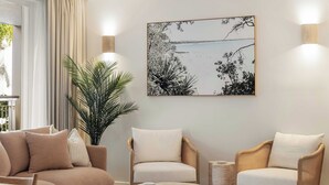 A modern living room with a sofa, two armchairs, a coffee table, and a large framed artwork on the wall. - Laguna 117 - Poolside, Near Beach (Noosa Heads)