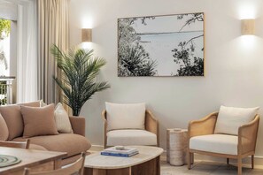 A modern living room with a sofa, two armchairs, a coffee table, and a large framed artwork on the wall.