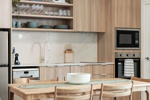 A modern kitchen with a built-in oven, microwave, and a dining area with a wooden table and chairs.