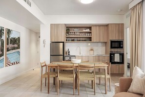 A modern kitchen with wooden cabinets, a built-in microwave, and a stainless steel refrigerator.