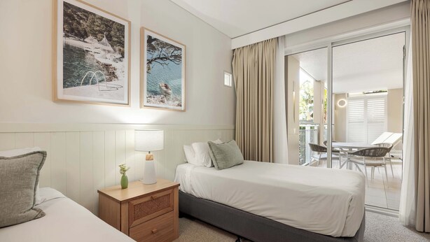 A hotel room with a bed, bedside table, lamp, and two framed pictures on the wall. - Laguna 117 - Poolside, Near Beach (Noosa Heads)