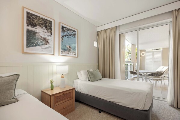 A hotel room with a bed, bedside table, lamp, and two framed pictures on the wall.