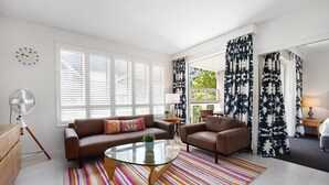 A modern living room with a sofa, armchair, glass coffee table, and striped rug. - Laguna 136 - Resort-Style, Steps to Beach (Noosa Heads)