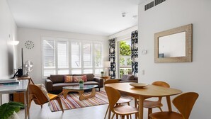A modern living room with a sofa, coffee table, dining table, and chairs. - Laguna 136 - Resort-Style, Steps to Beach (Noosa Heads)