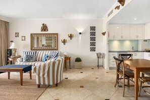 Ein Wohnzimmer mit einer Couch, einem Esstisch und einer Küchenzeile mit Schränken und einem Spülbecken.