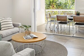 A modern living room with a sofa, a round coffee table, and a dining area with chairs and a table.
