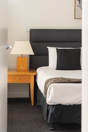 Une chambre d’hôtel avec un lit, une table de chevet avec une lampe et un tableau encadré au mur.