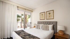 A hotel room with a bed, a nightstand, a lamp, and two framed pictures on the wall. - Laguna 621 - Oasis on Hastings St (Noosa Heads)
