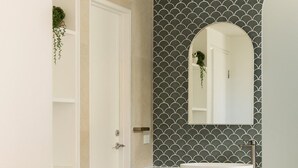 A bathroom with a white vanity, a mirror, and a tiled backsplash. - Laguna 621 - Oasis on Hastings St (Noosa Heads)