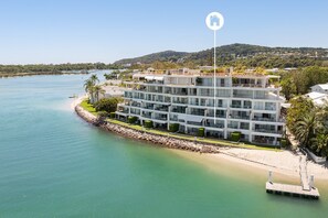 A multi-story hotel with balconies, located near a body of water with a dock.
