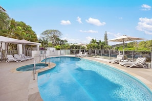 Relax by the pool surrounded by lush greenery and comfortable lounge chairs.