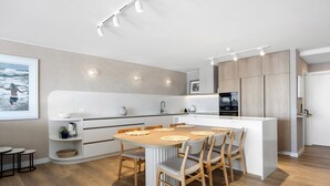A modern kitchen with a central island, wooden chairs, and a dining table. - Las Rias, Riverside Luxury Bliss (Noosa Heads)
