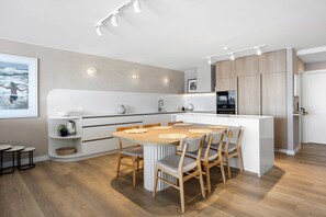 A modern kitchen with a central island, wooden chairs, and a dining table. - Las Rias, Riverside Luxury Bliss (Noosa Heads)