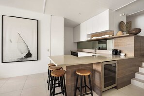 A modern kitchen with a large island, bar stools, and a framed picture on the wall.