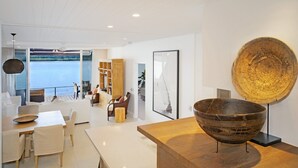 Een modern interieur met een eethoek, een grote houten schaal in het zicht, en uitzicht op het water.